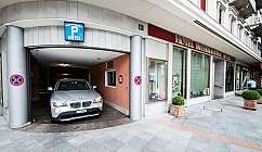 Voiture grise garée à l'entrée du parking d'un hôtel avec enseigne Hotel International Au Lac