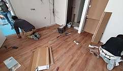 Deux ouvriers installent un parquet en bois.