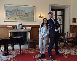 A young woman and a man in a refined environment with a piano.