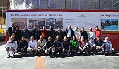 Des personnes souriantes posent devant un panneau d'information.