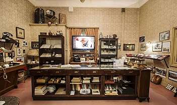 Sala di museo con mobili antichi, libri, fotografie e oggetti d'epoca esposti