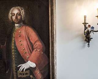 A portrait of a man in historical clothing next to a decorative lamp.