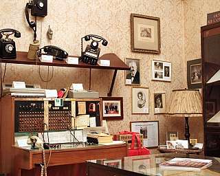 Intérieur d'un bureau historique avec des téléphones et des photographies anciennes.