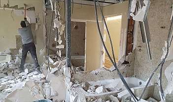 A worker is demolishing walls in a bathroom under renovation.
