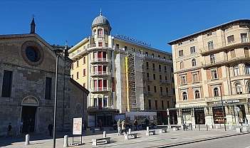 View of a square with a church and hotel under renovation.