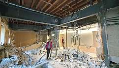 Workers in a demolition environment with debris and equipment.