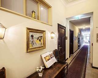 Interno di un corridoio con quadri e lampade decorative.