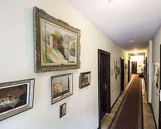 Corridoio decorato con quadri e tappeto, porte a sinistra.