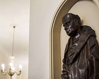 Scultura in legno di un monaco su parete interna.