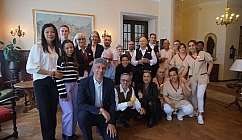 Groupe de personnes en tenue formelle et uniformes dans une pièce aux murs clairs et au sol en bois