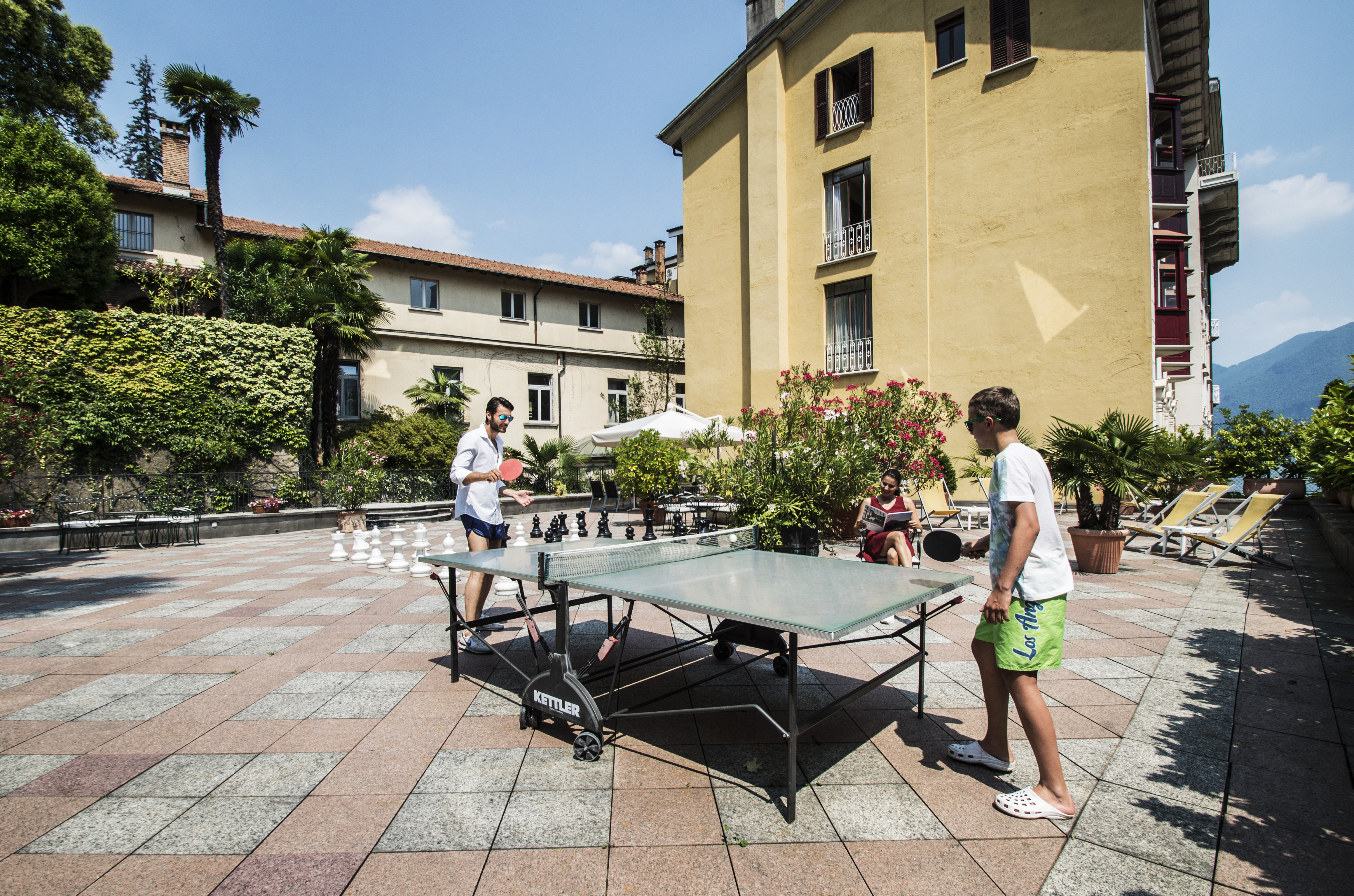 Two boys play ping pong in the sun