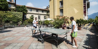 Two boys play ping pong in the sun