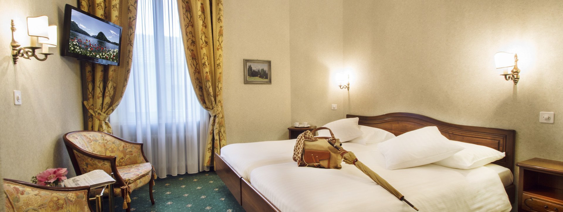 A bag and an umbrella lie on the double bed with white duvet cover