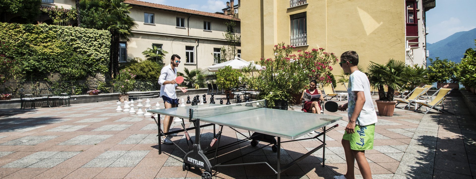 Two boys play ping pong in the sun