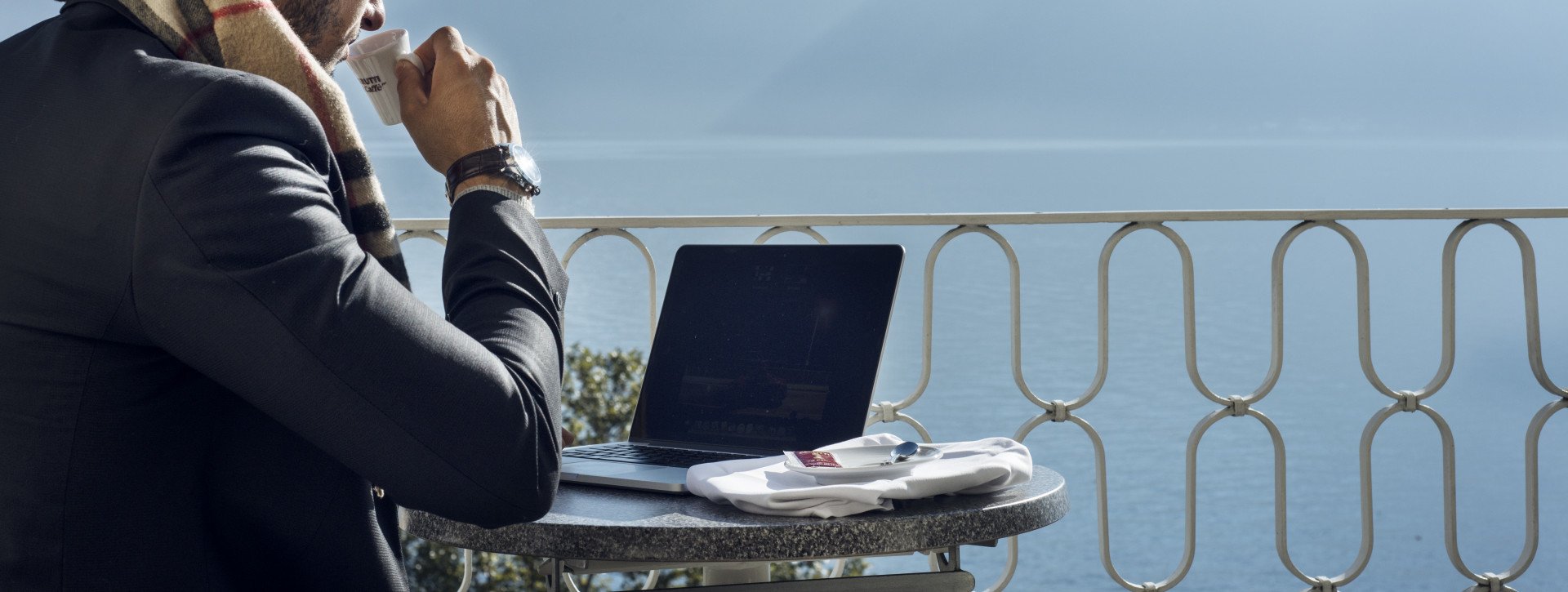 A man works mobile on a balcony with lake view